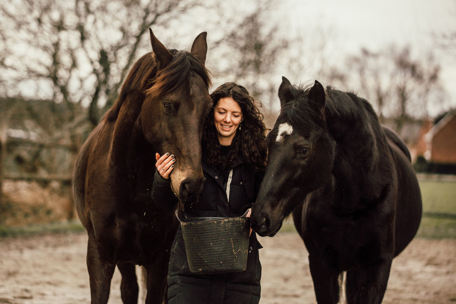 Marjo Lebbe standing between her two horses